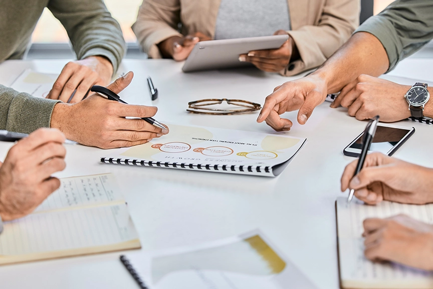 Besprechungstisch mit Arbeitsunterlagen und Händen